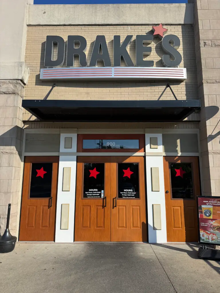 Front entrance of Drakes restaurant with large sign and red stars on wooden doors.