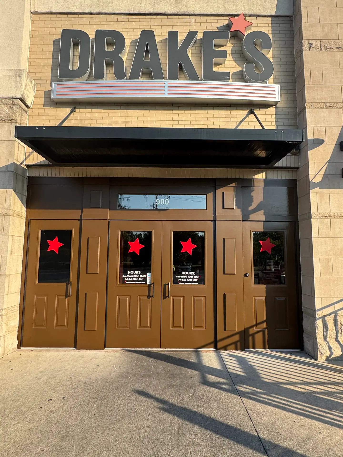 Front entrance of Drake’s restaurant with brown doors and red star decals on each door. - My Personal Painter Front entrance of Drake’s restaurant with brown doors and red star decals on each door.