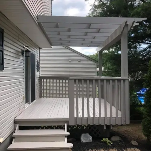 A small, light-gray wooden deck with railings and a pergola attached to a house, accessed by three steps. - My Personal Painter - My Personal Painter A small, light-gray wooden deck with railings and a pergola attached to a house, accessed by three steps.