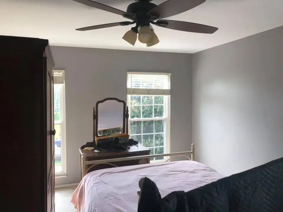 A bedroom with a bed, a dresser with a mirror, and a ceiling fan. - My Personal Painter - My Personal Painter After: bedrooms with wallpaper borders painted gray
