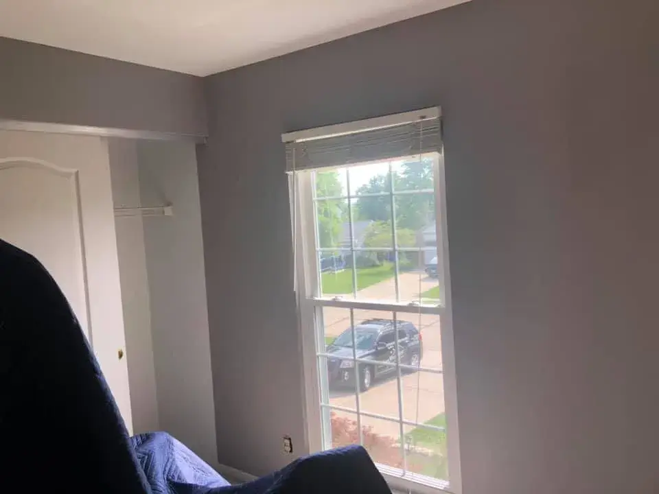 A bedroom with grey walls and a window looking out onto a residential street with a parked police car. - My Personal Painter - My Personal Painter After: bedrooms with wallpaper borders painted gray