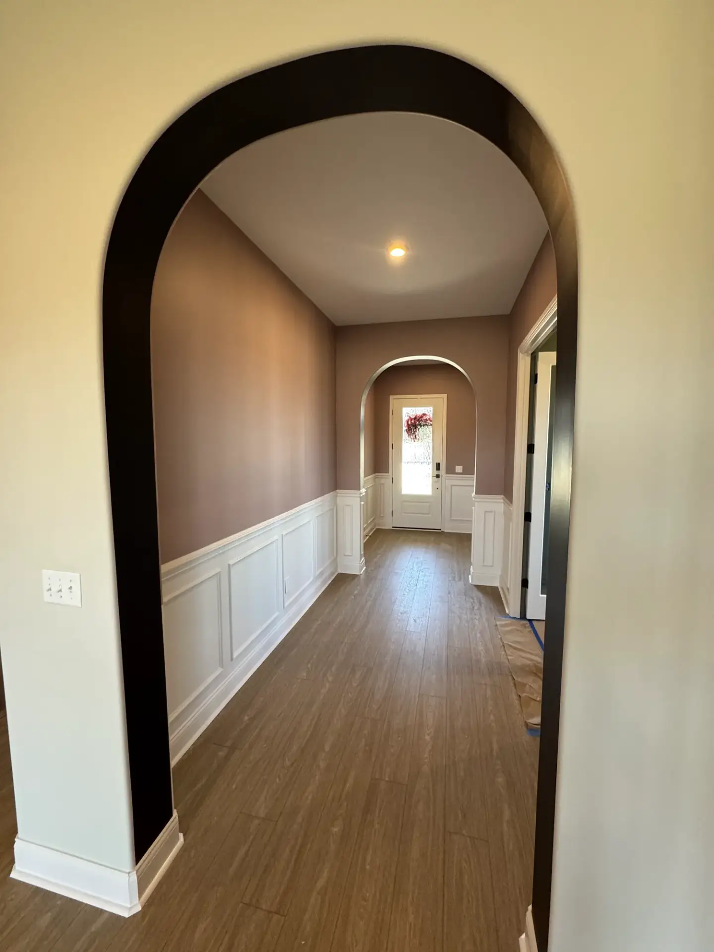 Black painted archway framing a taupe hallway with white wainscoting