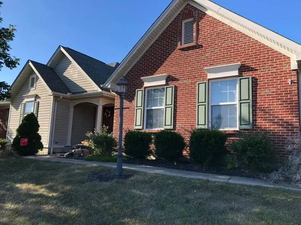 A brick and tan-sided house with green shutters and a front lamp post. - My Personal Painter - My Personal Painter In progress: brick and siding ranch: entry, doors and garage door