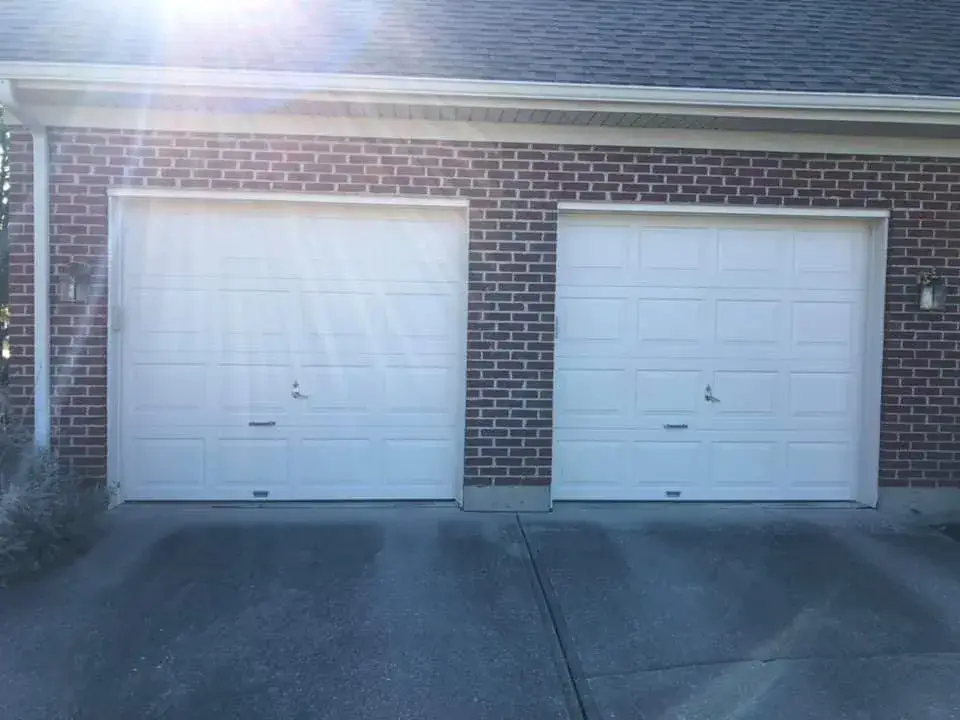 Two white paneled garage doors on a red brick house. - My Personal Painter - My Personal Painter In progress: brick and siding ranch: entry, doors and garage door