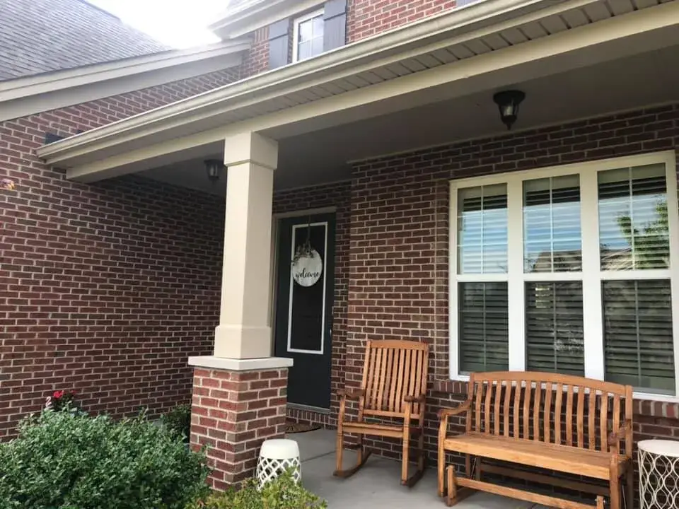 A brick house porch with a wooden rocking chair, a wooden bench, and a welcome sign on the front door. - My Personal Painter - My Personal Painter After: brick and tan siding house exterior painted