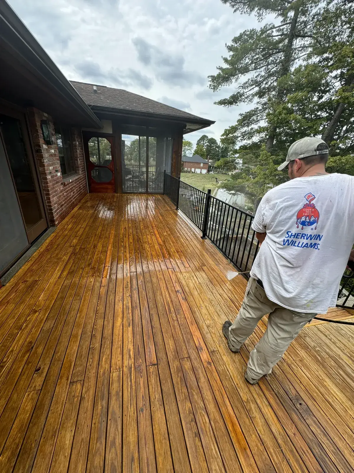 After: brick home deck pressure washed, by a screened porch with a red wood door