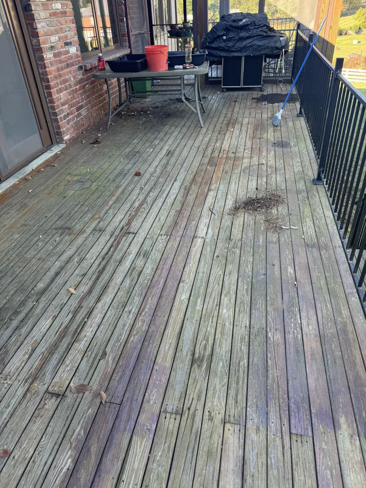 Before: brick home deck pressure washed, by a screened porch with a red wood door