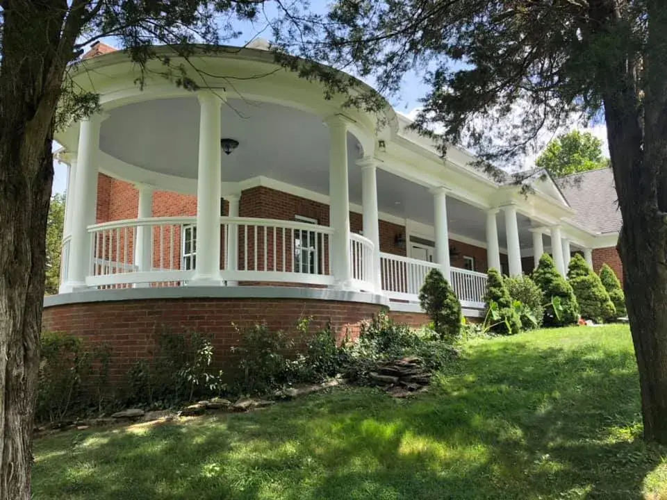 A large brick house with a curved, white-columned porch overlooking a grassy lawn. - My Personal Painter - My Personal Painter After: brick home: round wraparound porch and rear deck with brick columns