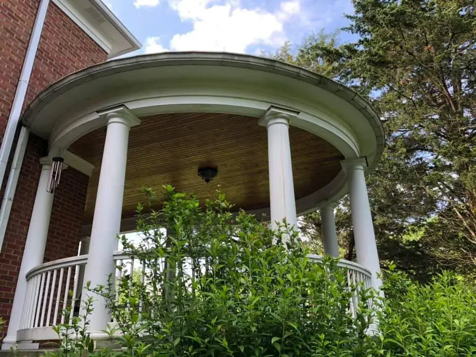 Before: brick home: round wraparound porch and rear deck with brick columns