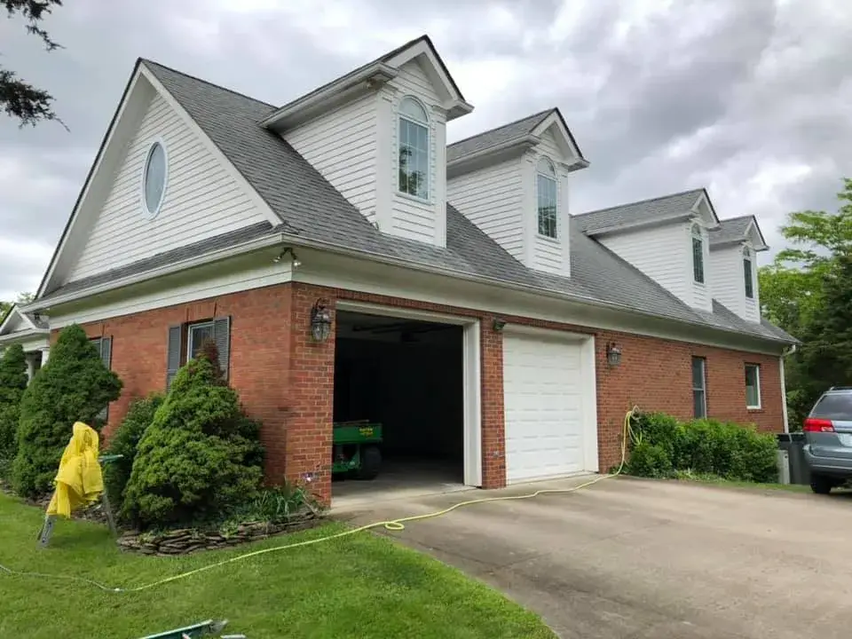 A two-story brick and white siding house with an attached garage and three dormer windows. - My Personal Painter - My Personal Painter In progress: brick home: round wraparound porch and rear deck with brick columns