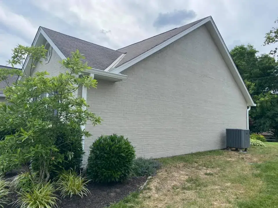 Side view of a house with light-colored brick siding and a gray shingled roof. - My Personal Painter - My Personal Painter After: brick ranch exterior painted light gray