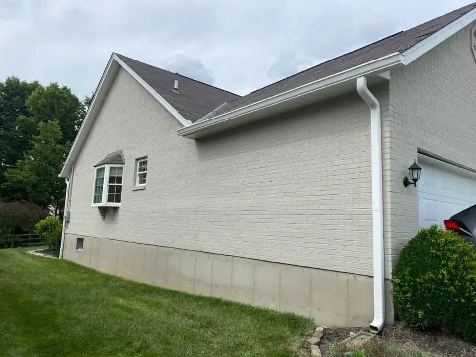 Side view of a light-colored brick house with a bay window and a garage. - My Personal Painter - My Personal Painter After: brick ranch exterior painted light gray