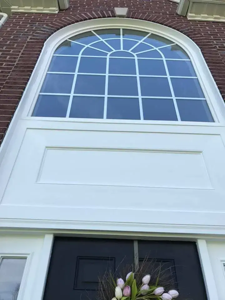 After: brick two-story front entry: rotted trim repaired, trim painted white, red door painted black