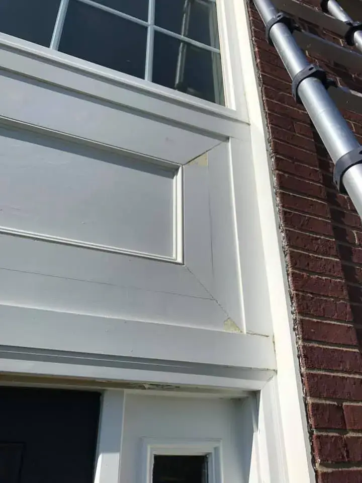 After: brick two-story front entry: rotted trim repaired, trim painted white, red door painted black