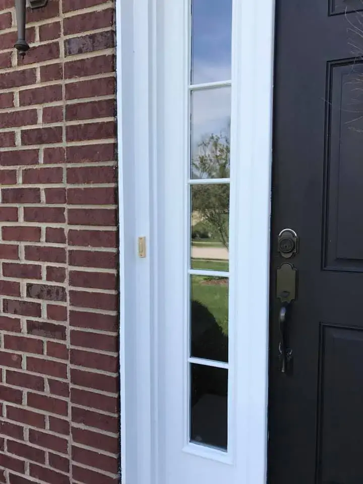 After: brick two-story front entry: rotted trim repaired, trim painted white, red door painted black