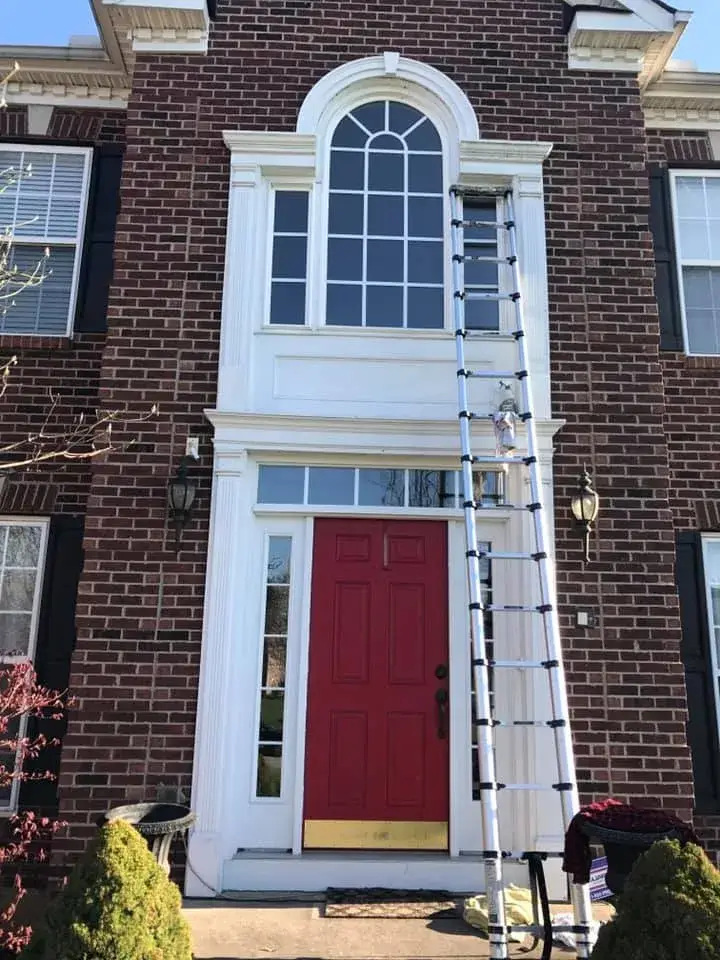 Before: brick two-story front entry: rotted trim repaired, trim painted white, red door painted black