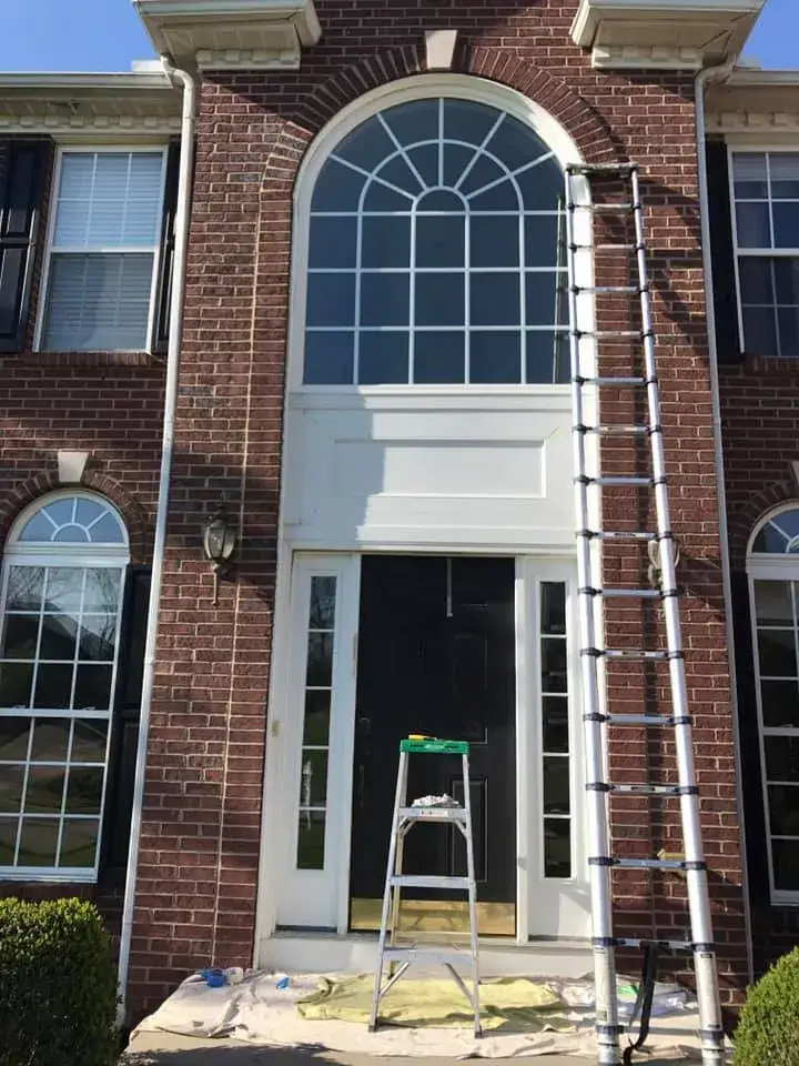 In progress: brick two-story front entry: rotted trim repaired, trim painted white, red door painted black