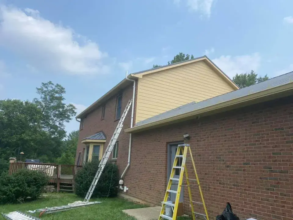 After: brick two-story house: siding and trim painted