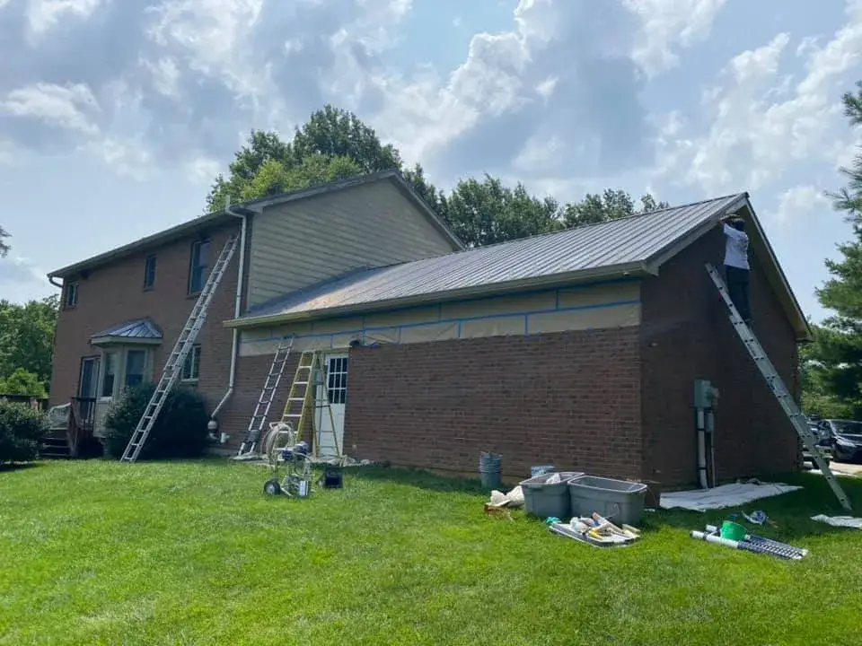 Workers using ladders to paint the exterior of a two-story brick and siding house. - My Personal Painter - My Personal Painter In progress: brick two-story house: siding and trim painted