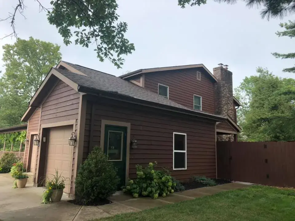 After: brown sided house with front porch and garage