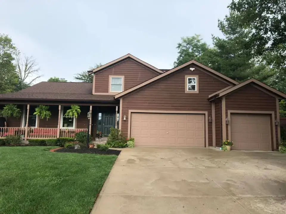 Before: brown sided house with front porch and garage