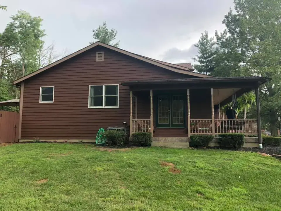 In progress: brown sided house with front porch and garage