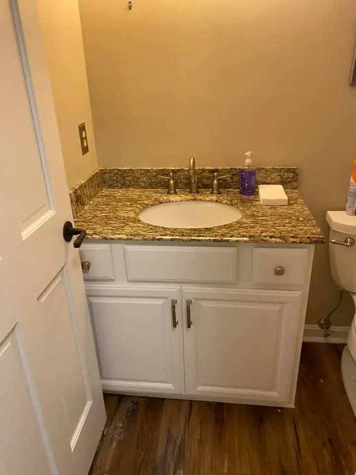 A white bathroom vanity with a granite countertop and oval sink. - My Personal Painter - My Personal Painter After: ceiling beams painted black, brick fireplace whitewashed, other rooms