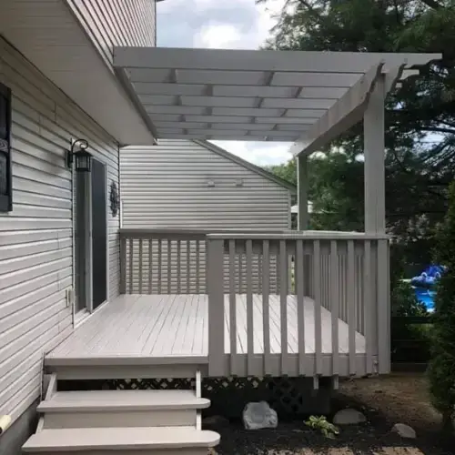 A gray wooden deck with matching stairs and an overhead pergola attached to the side of a house. - My Personal Painter - My Personal Painter After: deck and pergola painted gray