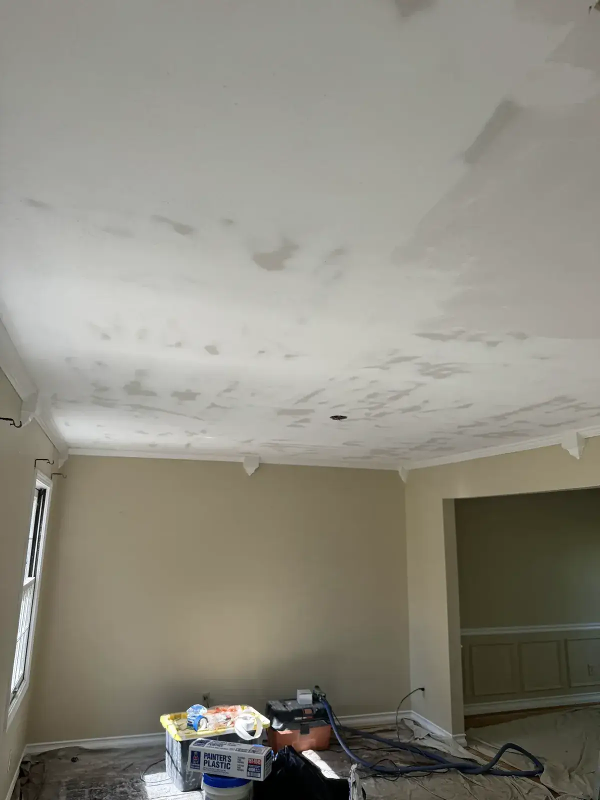A room with a partially painted white ceiling showing patches of drywall filler. - My Personal Painter - My Personal Painter In progress: dining room water-stained ceiling repaired