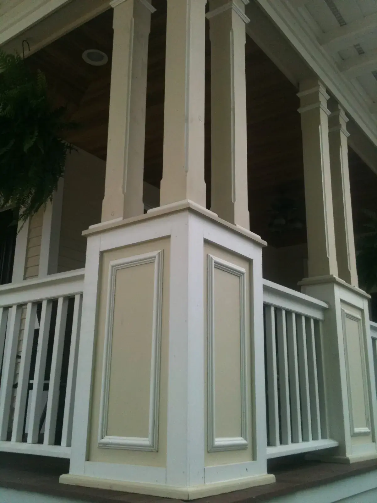 After: front porch with white railings and columns on a sided home