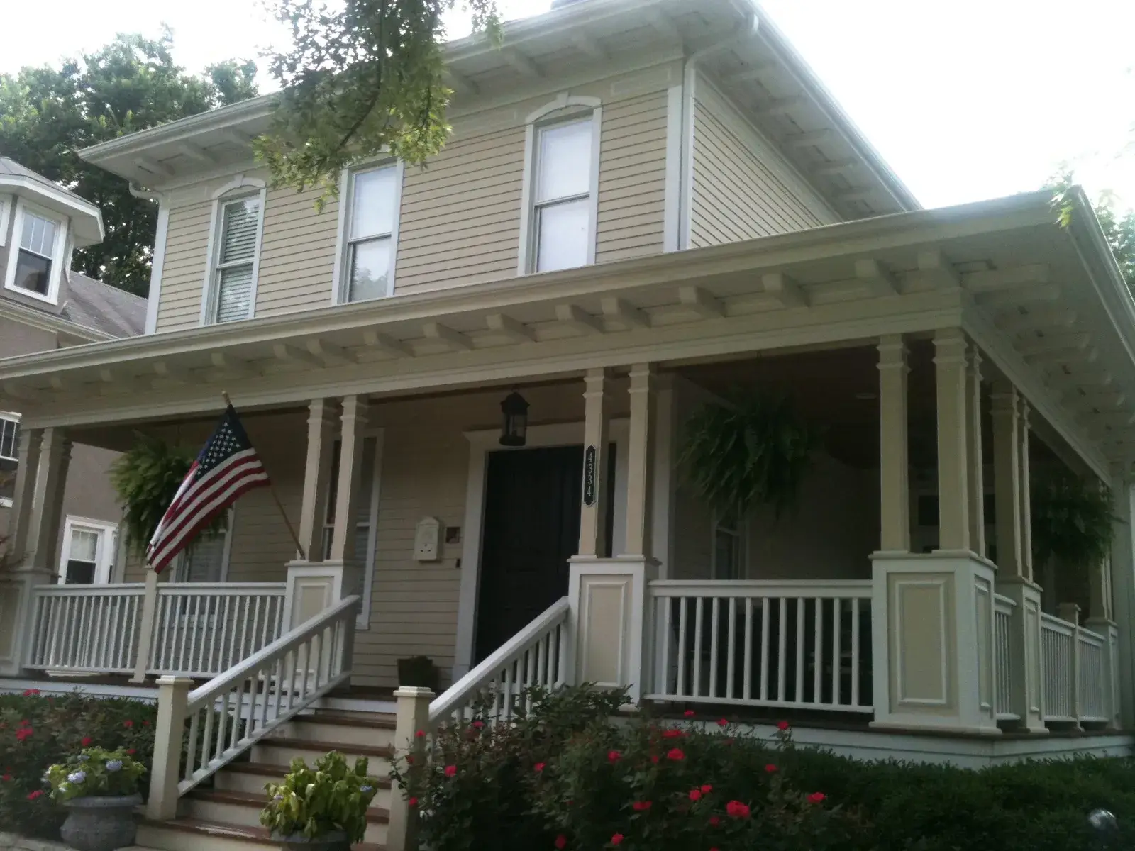 After: front porch with white railings and columns on a sided home