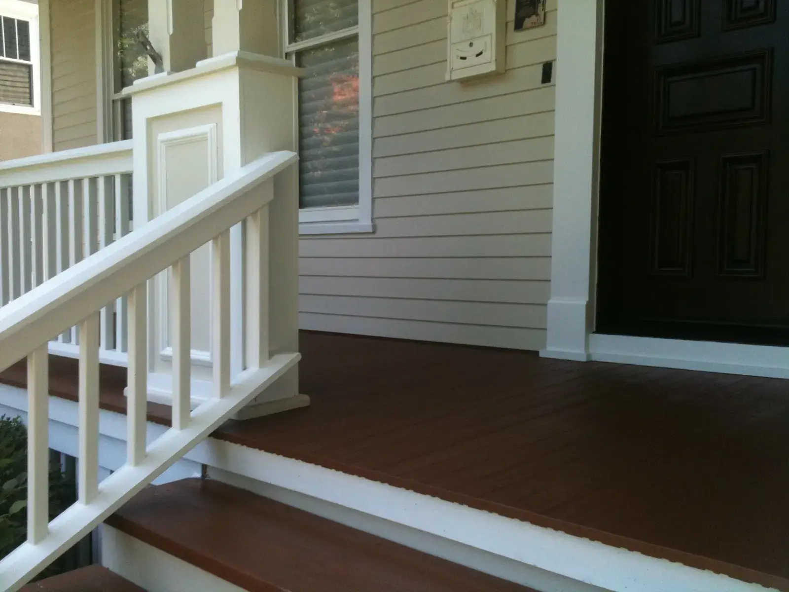 After: front porch with white railings and columns on a sided home