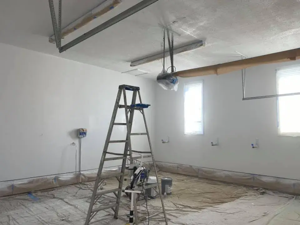 In progress: great room with tray ceiling and arched window, garage painted white