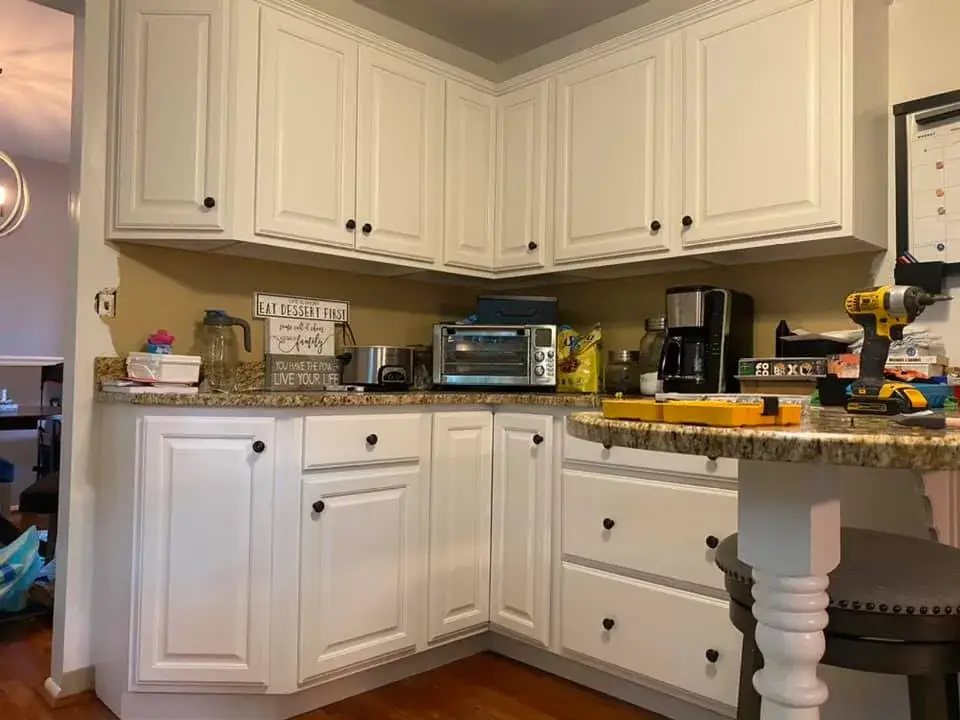 White kitchen cabinets with granite countertops and various small appliances on the counter. - My Personal Painter - My Personal Painter After: kitchen cabinets painted white, granite counters