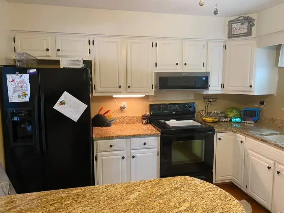 Kitchen with white cabinets, granite countertops, and black appliances. - My Personal Painter - My Personal Painter After: kitchen cabinets painted white, granite counters