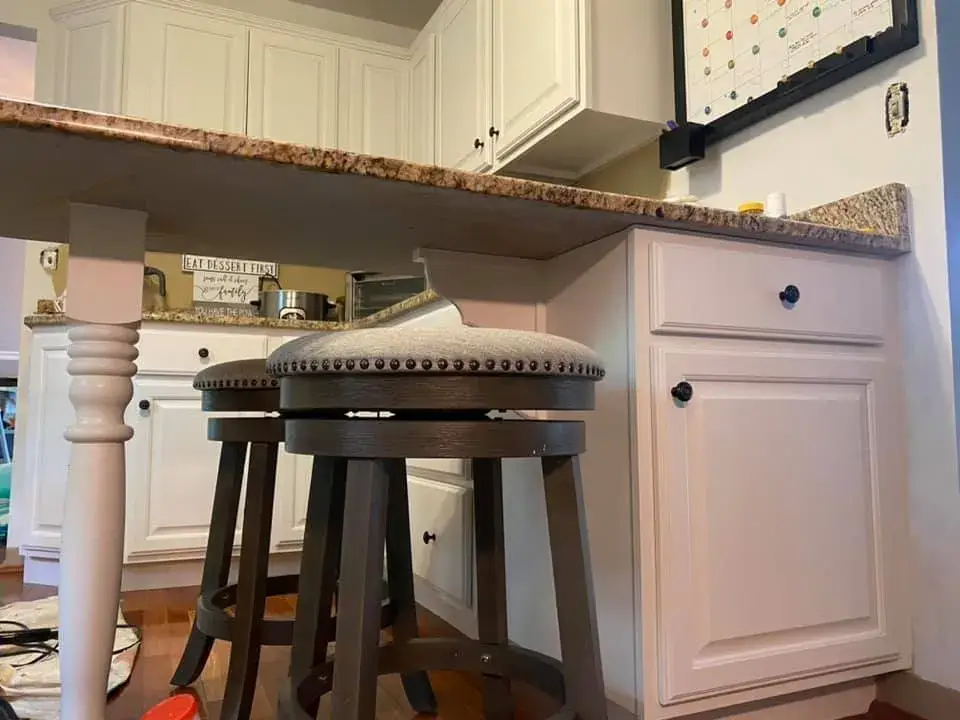 Two dark wood swivel bar stools with upholstered seats tucked under a granite kitchen island. - My Personal Painter - My Personal Painter After: kitchen cabinets painted white, granite counters