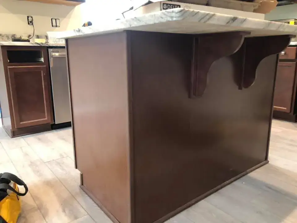 A dark wood kitchen island with a stone countertop and decorative corbels. - My Personal Painter - My Personal Painter Before: kitchen cherry cabinets painted black