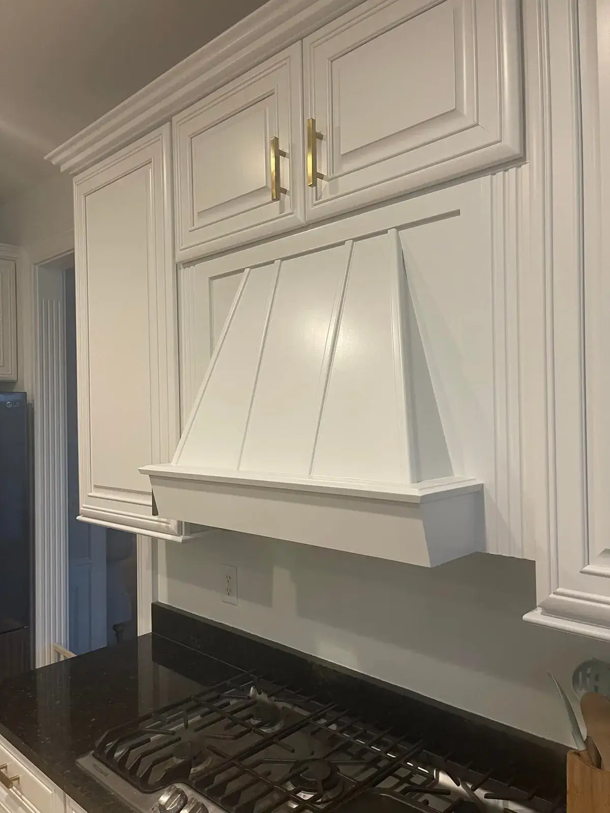 White kitchen range hood built into cabinetry above a gas stovetop. - My Personal Painter - My Personal Painter After: kitchen cherry cabinets to white with a green island, two-story great room, dining room and foyer