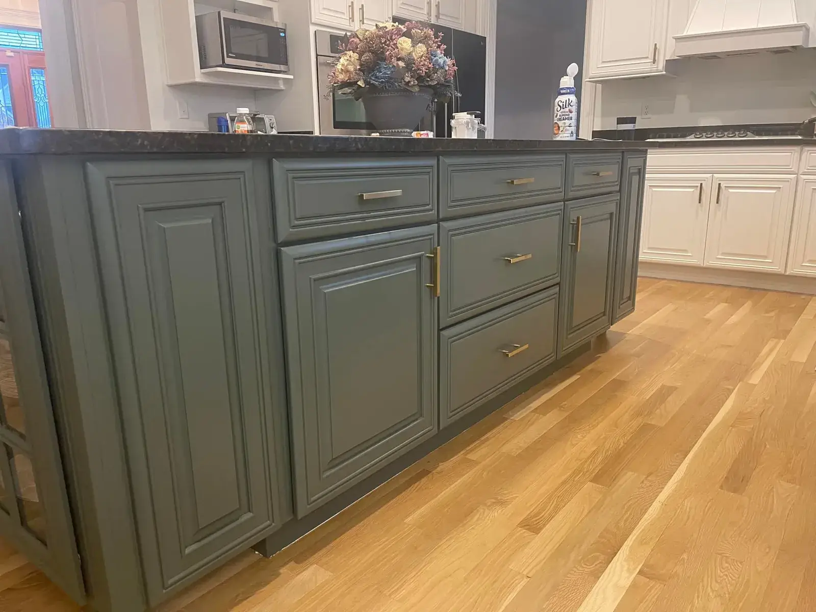 After: kitchen cherry cabinets to white with a green island, two-story great room, dining room and foyer