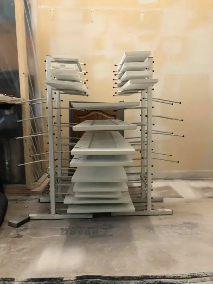 A drying rack holding multiple painted cabinet doors in a room under renovation. - My Personal Painter - My Personal Painter In progress: kitchen dark cabinets painted white