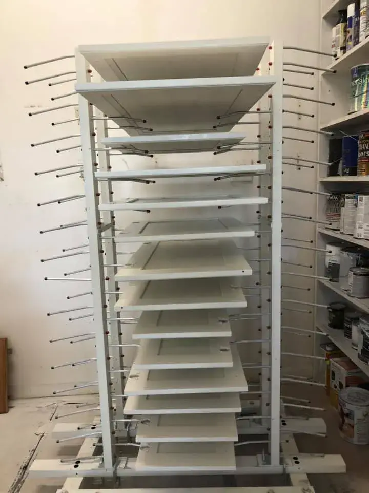 White cabinet doors drying on a metal rack. - My Personal Painter - My Personal Painter In progress: kitchen dark cabinets painted white
