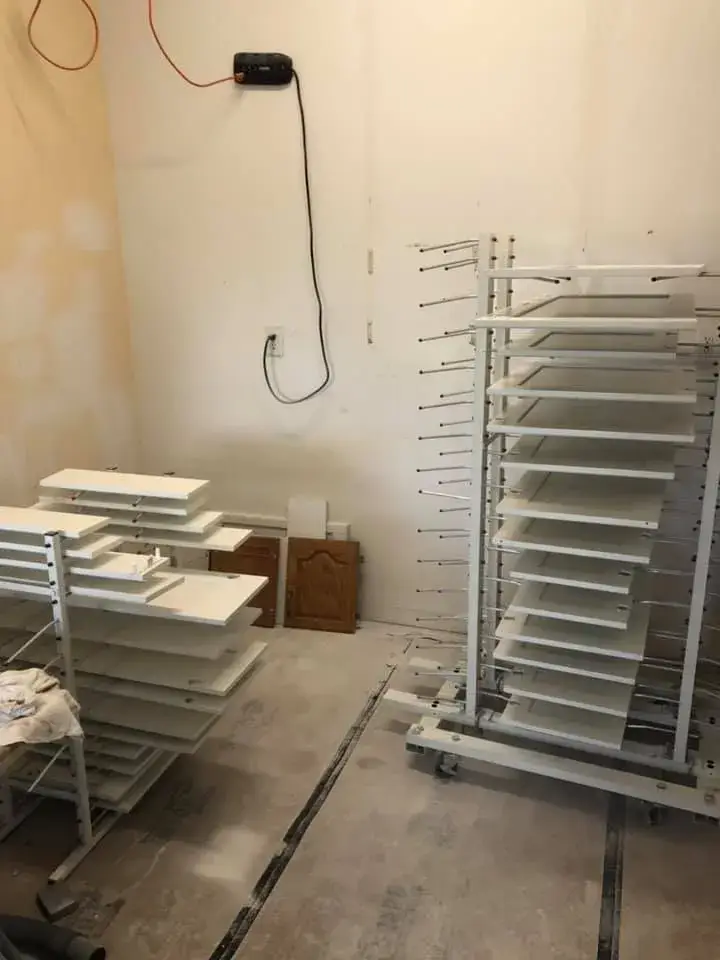 Two drying racks holding painted cabinet doors in a room under renovation. - My Personal Painter - My Personal Painter In progress: kitchen dark cabinets painted white