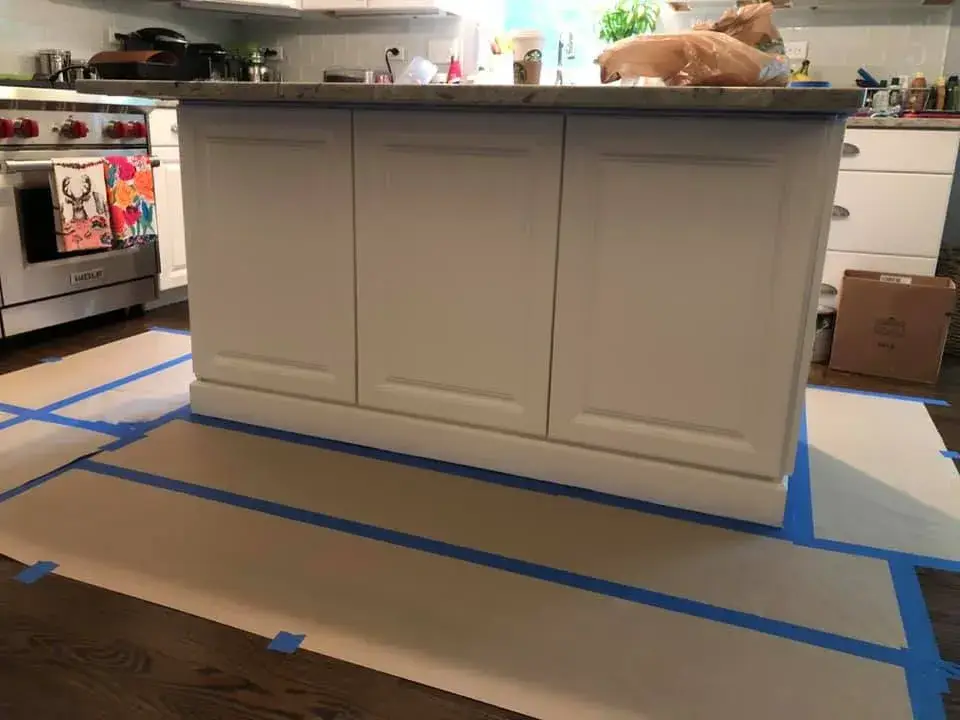 A kitchen island surrounded by painters tape and paper on the floor for home renovation. - My Personal Painter - My Personal Painter Before: kitchen island painted navy