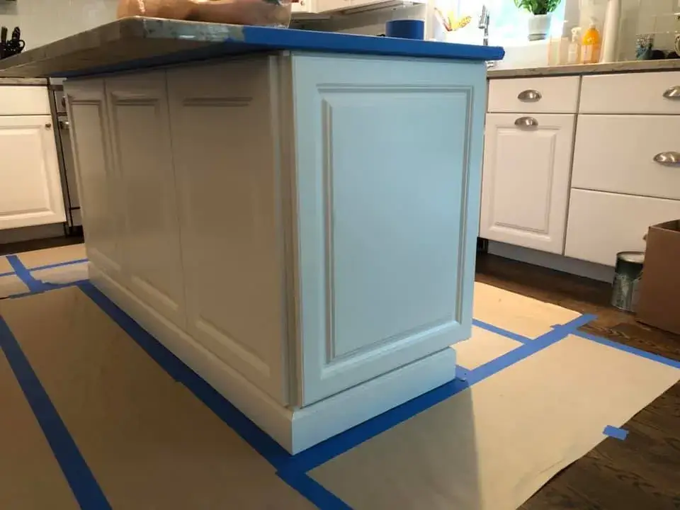 A white kitchen island partially covered in blue painters tape during a renovation project. - My Personal Painter - My Personal Painter Before: kitchen island painted navy