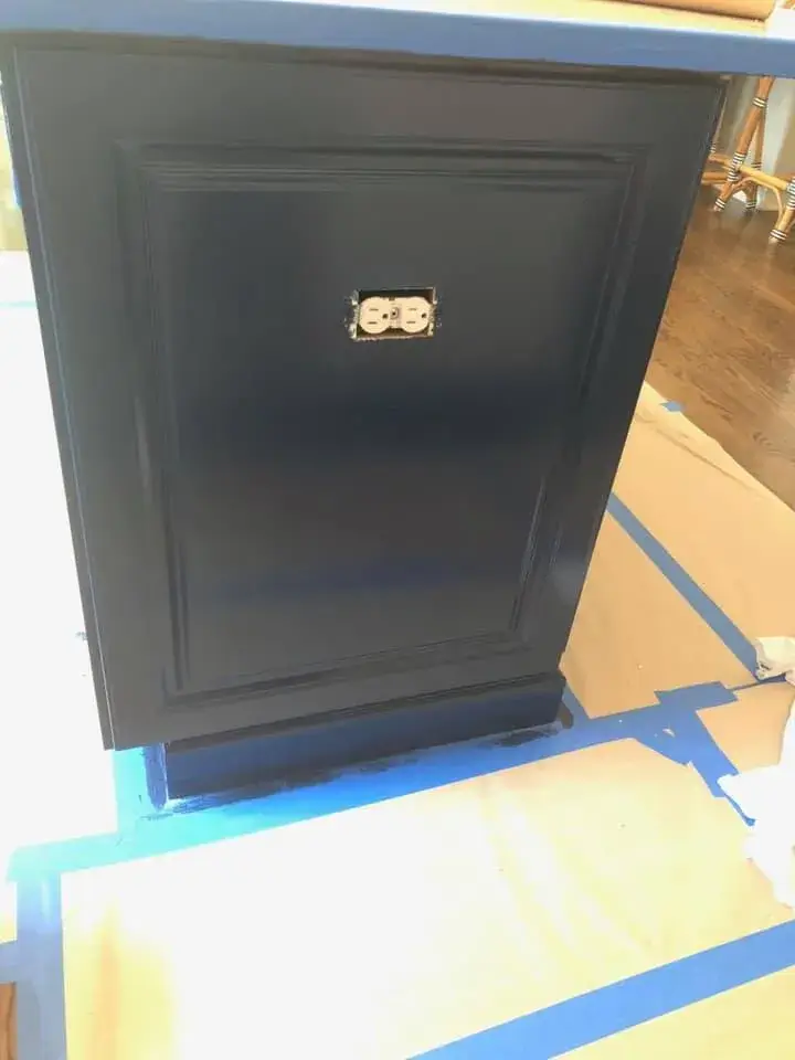 A dark blue kitchen cabinet end panel with an electrical outlet installed in the center. - My Personal Painter - My Personal Painter In progress: kitchen island painted navy