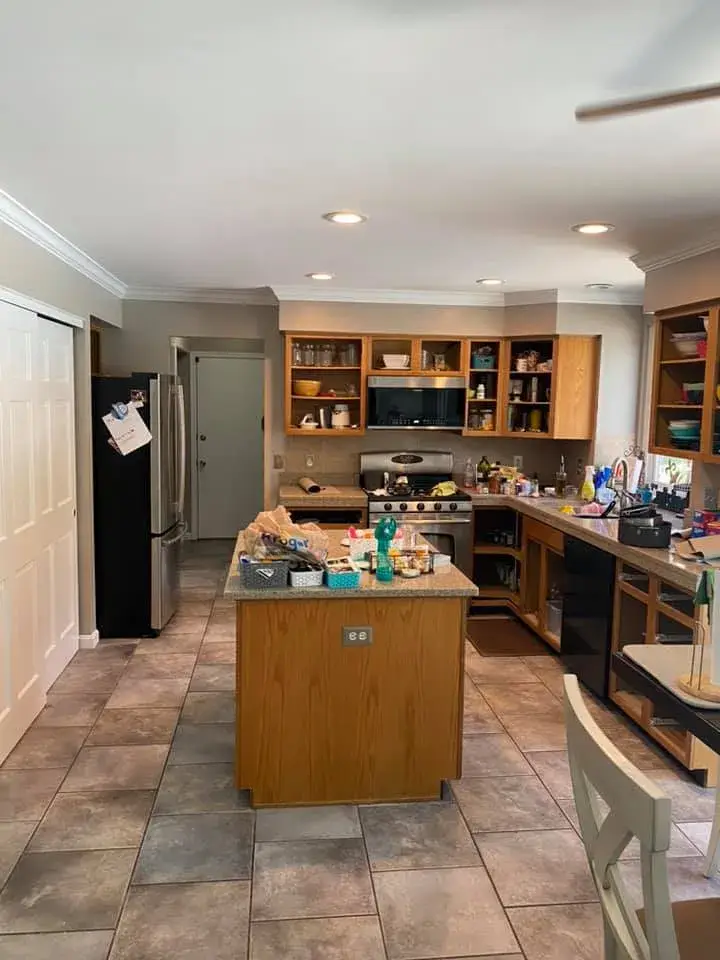 A kitchen with wooden cabinets, a central island, and tiled floors. - My Personal Painter - My Personal Painter Before: kitchen painted white, living room and dining room repainted