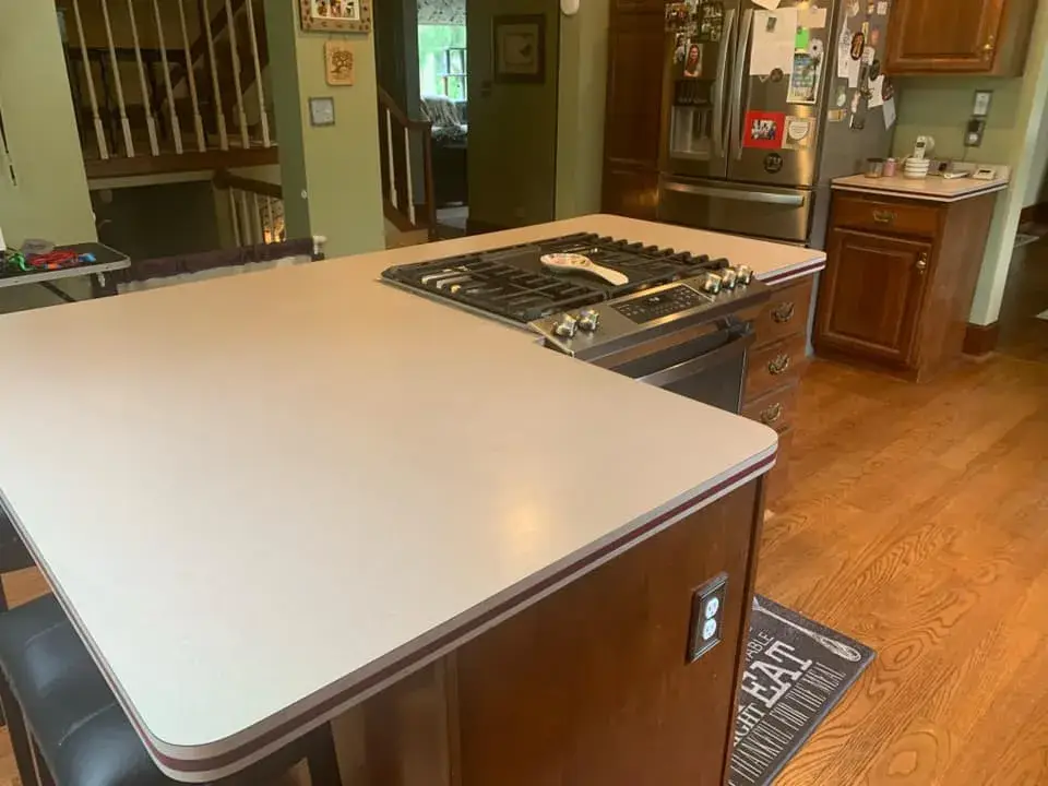 Kitchen island with a built-in gas cooktop and light-colored countertop. - My Personal Painter - My Personal Painter Before: kitchen wood cabinets painted dark