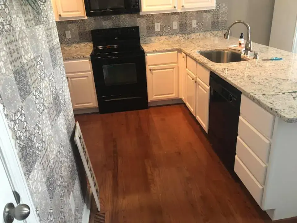 After: kitchen wood cabinets painted white (patterned tile wall, HOME sign)