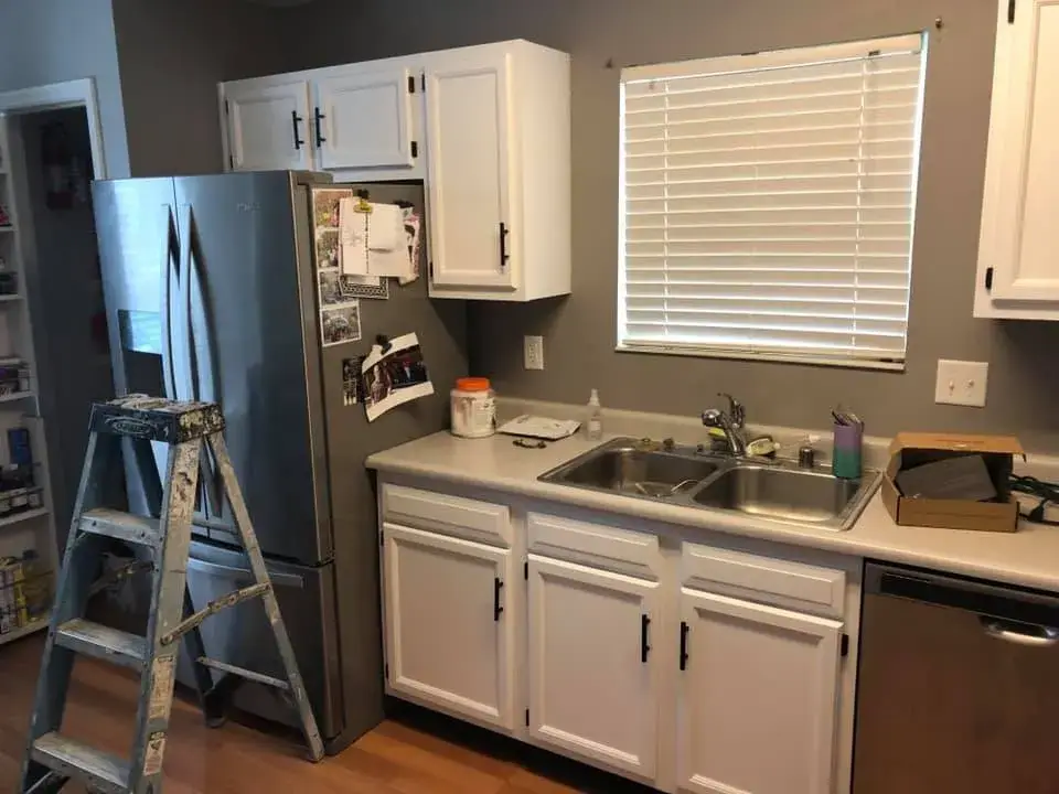 After: kitchen wood cabinets painted white (patterned tile wall, HOME sign)