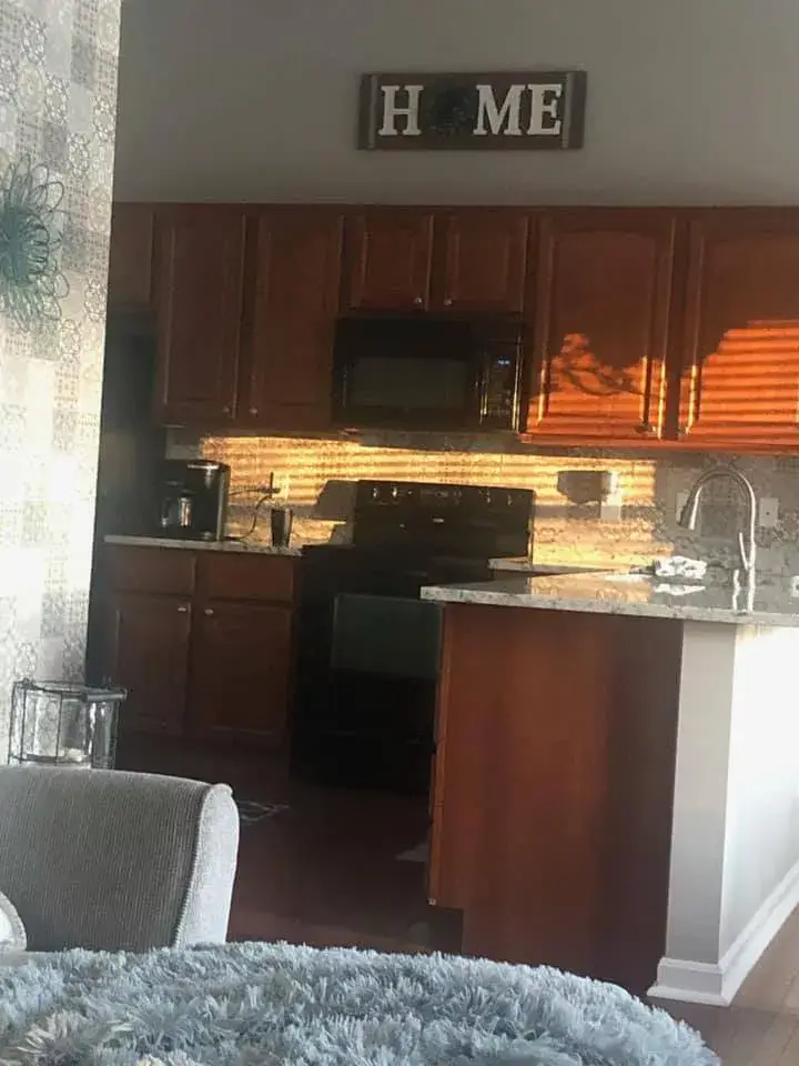 Before: kitchen wood cabinets painted white (patterned tile wall, HOME sign)
